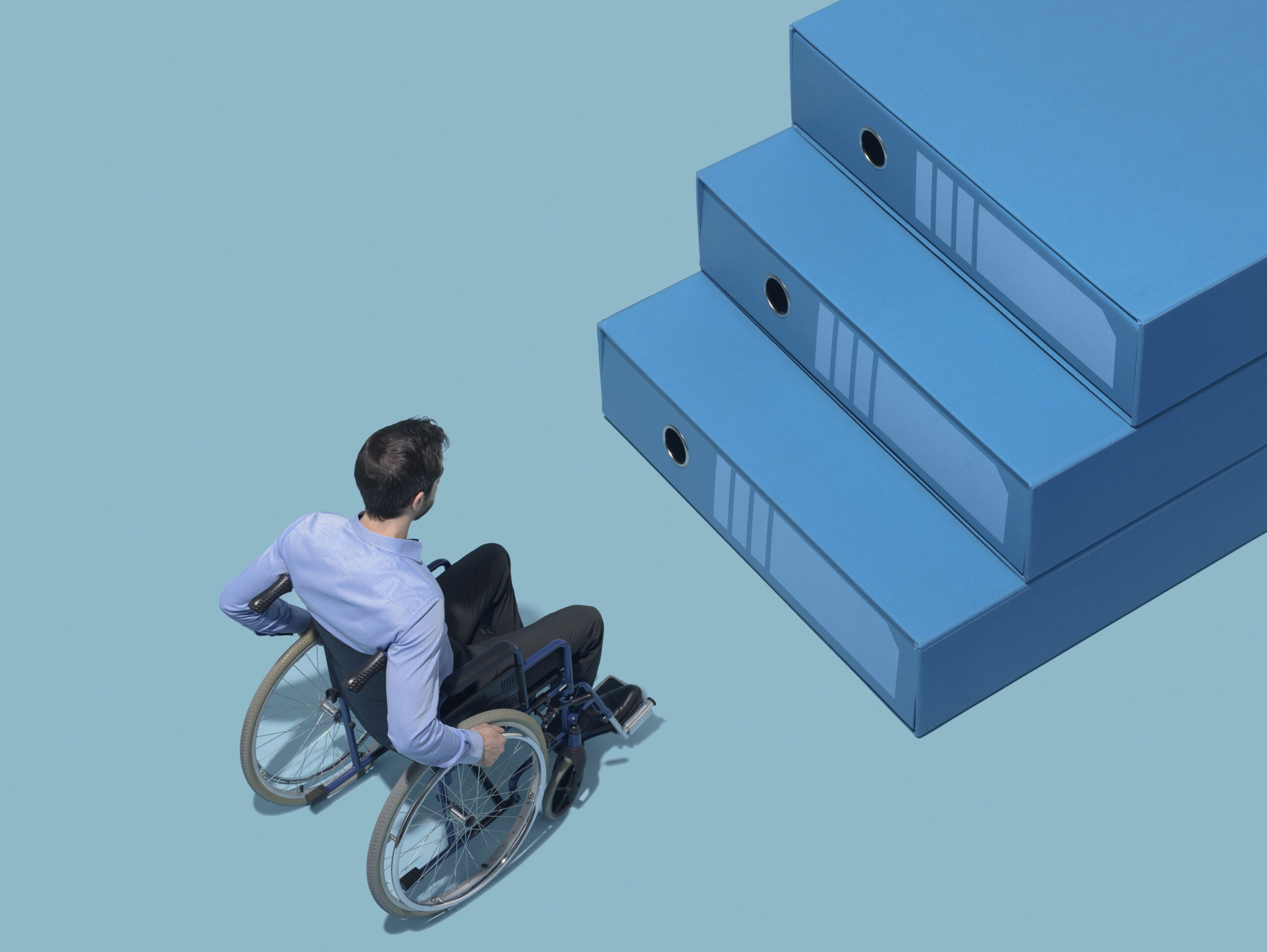 Man in wheelchair stopping in front of a staircase made of folders